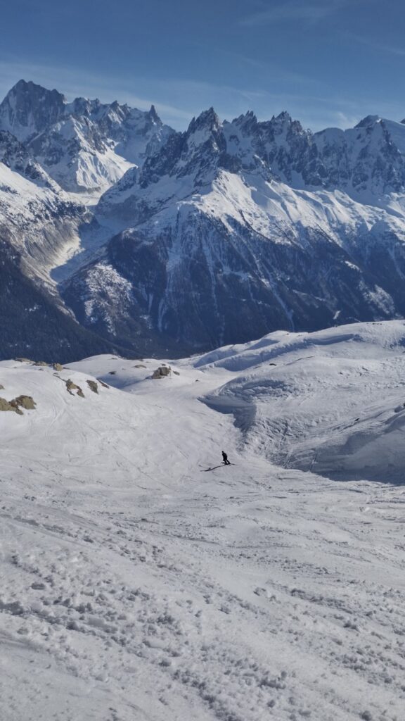 A skier descending with mountains in the background