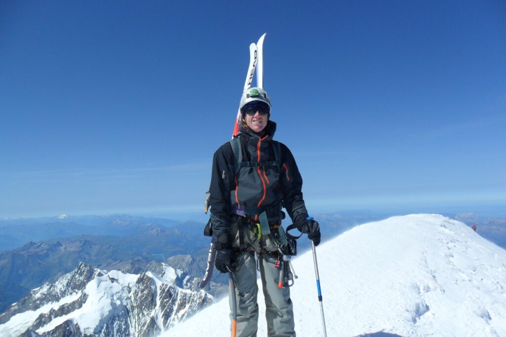 Person standing on top of Mont Blanc with skis