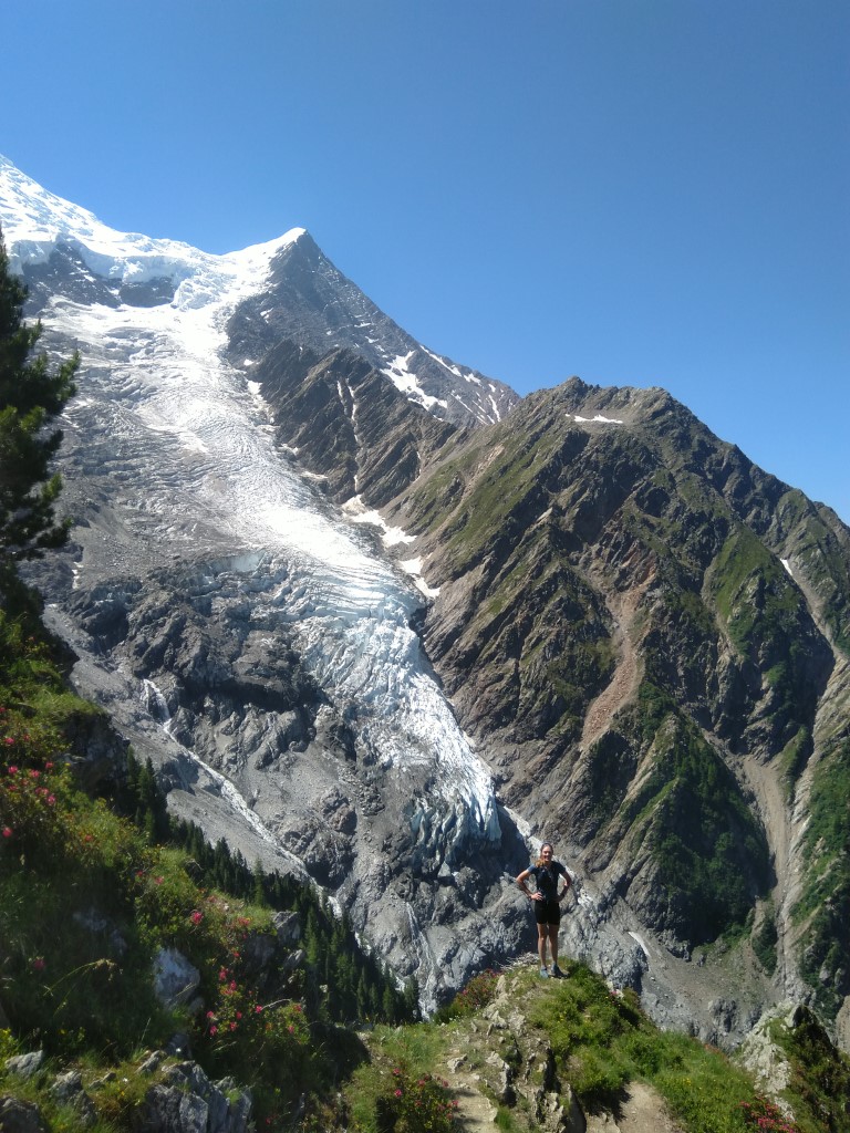 Person standing on a path in front of a steep glacier on the hike up to La Jonction