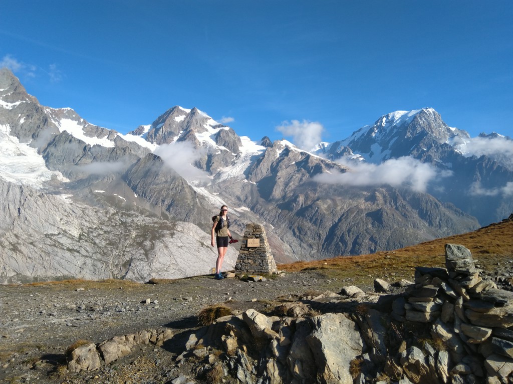 Hiker standing by a stone pillar in front of Mont Blanc on the TB