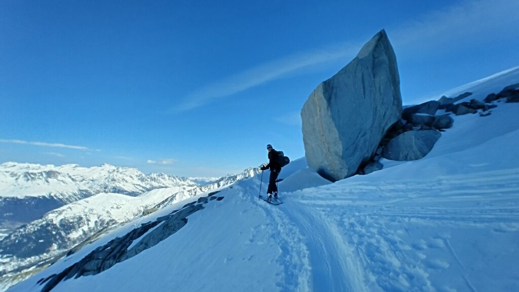 Skier next to draatic boulder