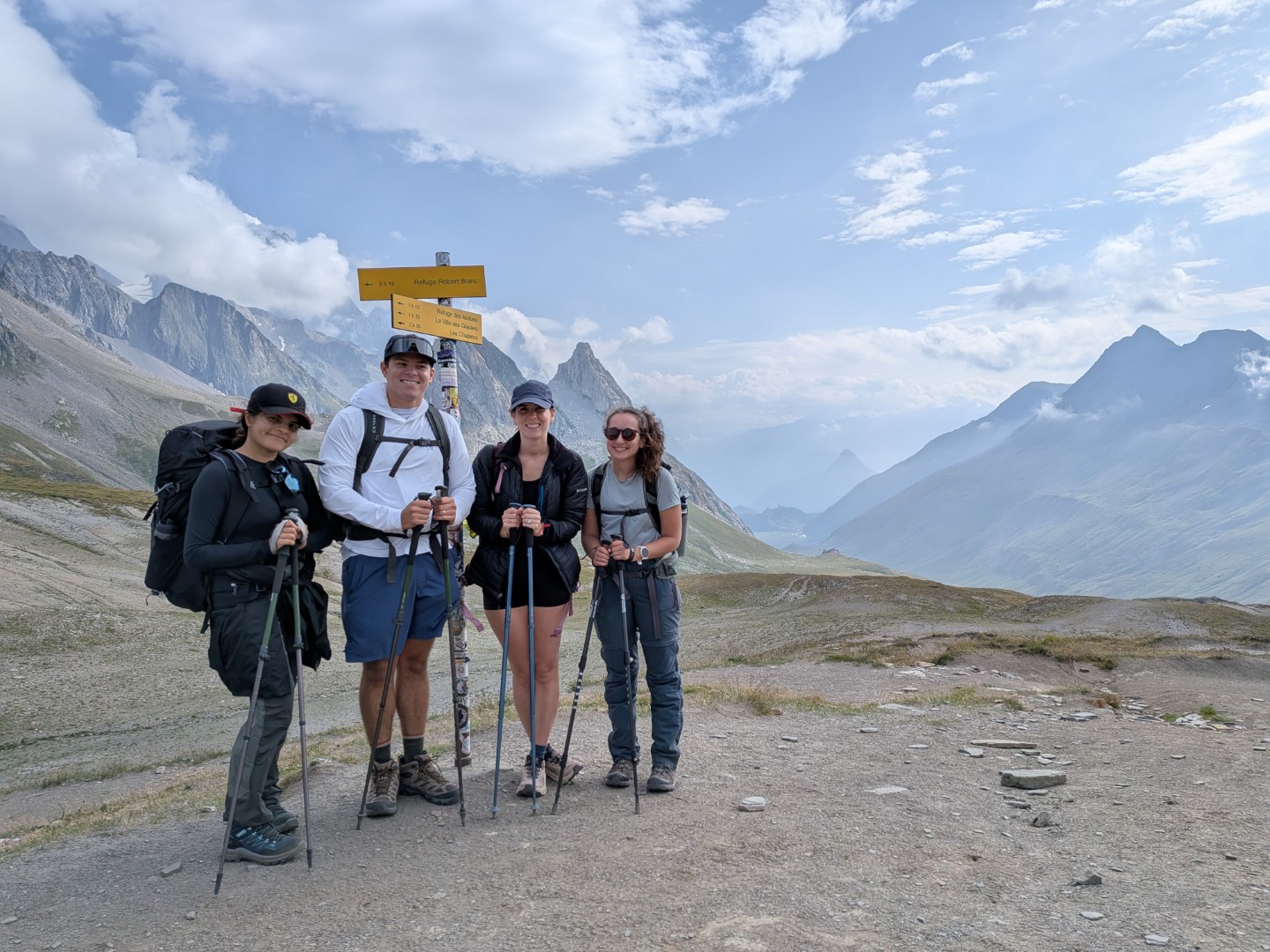 Four hikers with backpacks at a col in the Alps